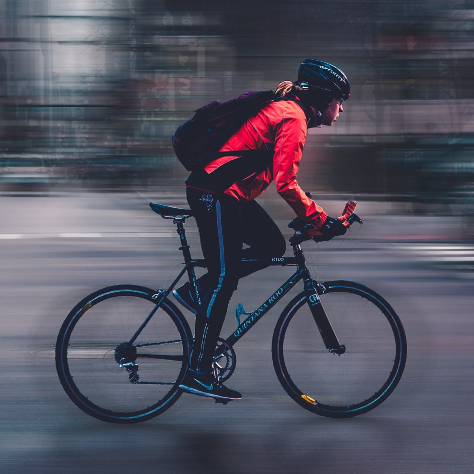 Side view of a woman on a road bike in a city, going fast